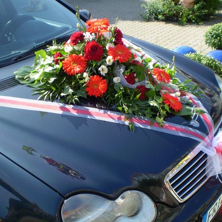 Ein Blumenstrauß mit roten Rosen auf einem schwarzen Auto