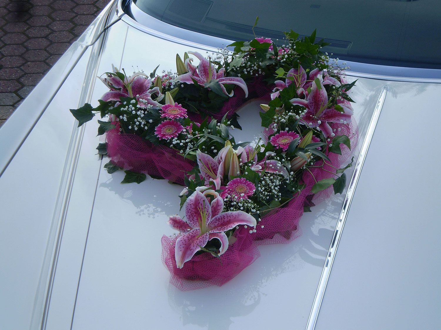 Ein weißes Auto mit einem rosa Blumenstrauß drauf